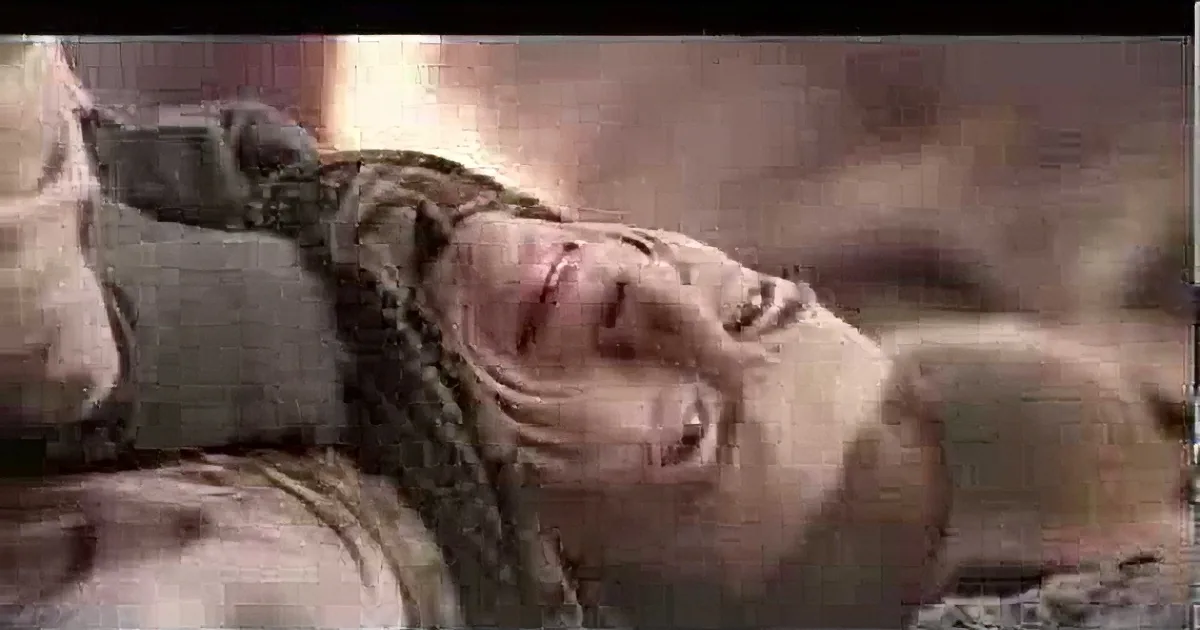 A person with long hair is lying down, appearing distressed or injured, with a blurred background.