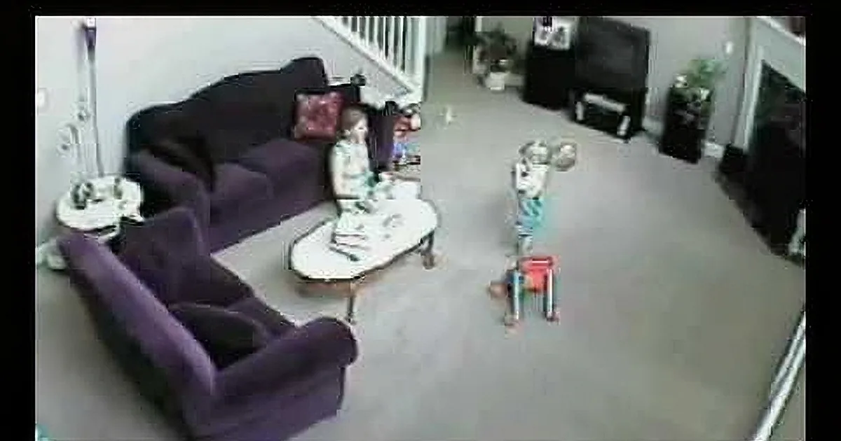 A person in a purple outfit is dancing in a living room with a couch, coffee table, and staircase.