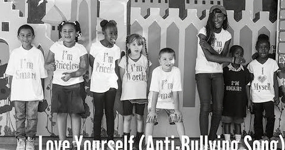 Children in white shirts with affirmations stand in front of a decorative fence.