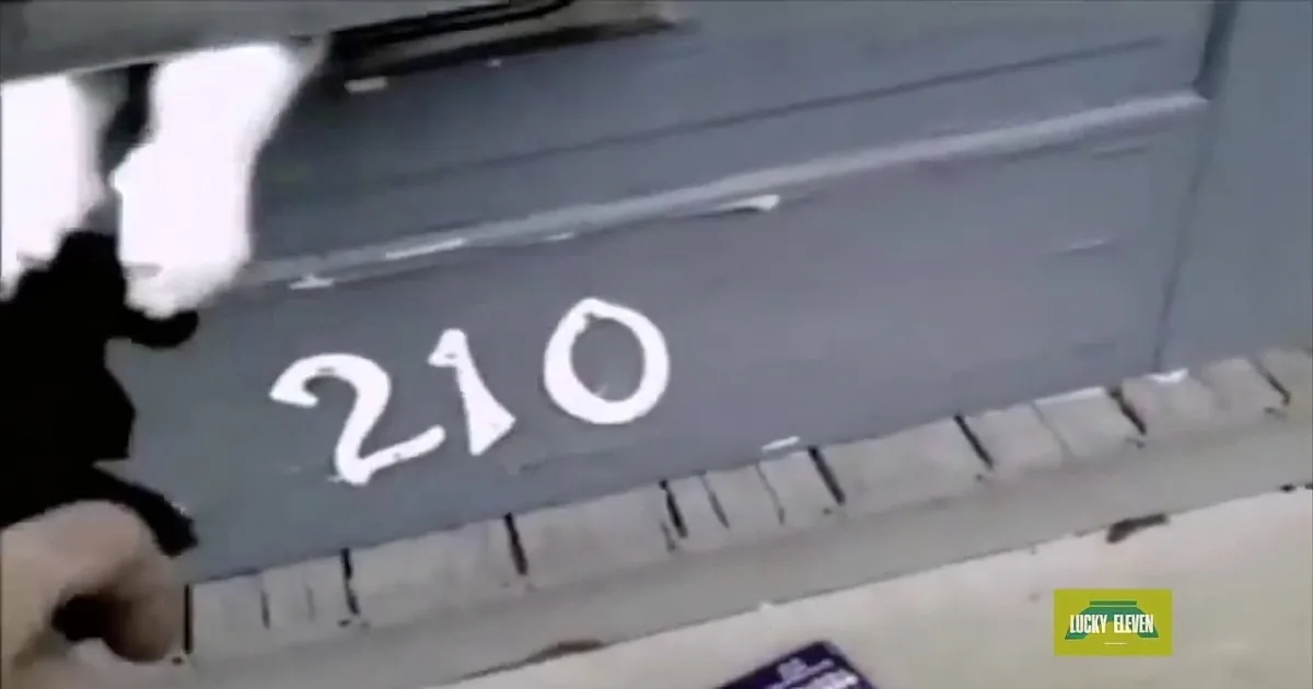 A person is spray painting "210" on a metal surface, with a Lucky Eleven logo in the corner.