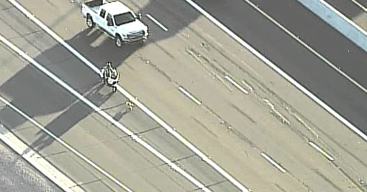 A white pickup truck is stopped on a highway, with a cyclist nearby.