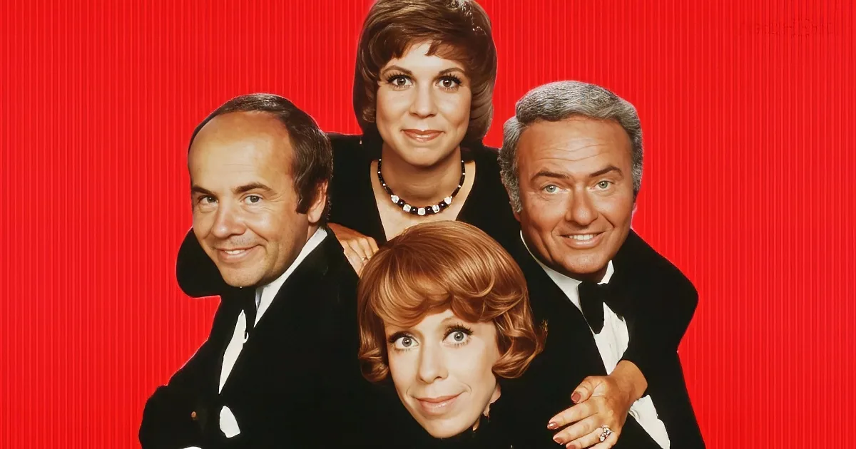 A group of four people in formal attire posing together against a red background.