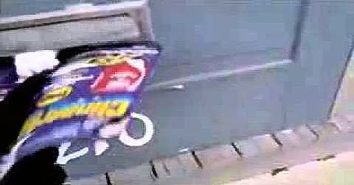 A person holds a bag of Lay's potato chips near a gray wall.