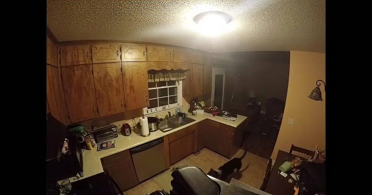 Kitchen with wooden cabinets, cluttered countertops, and a window above the sink.