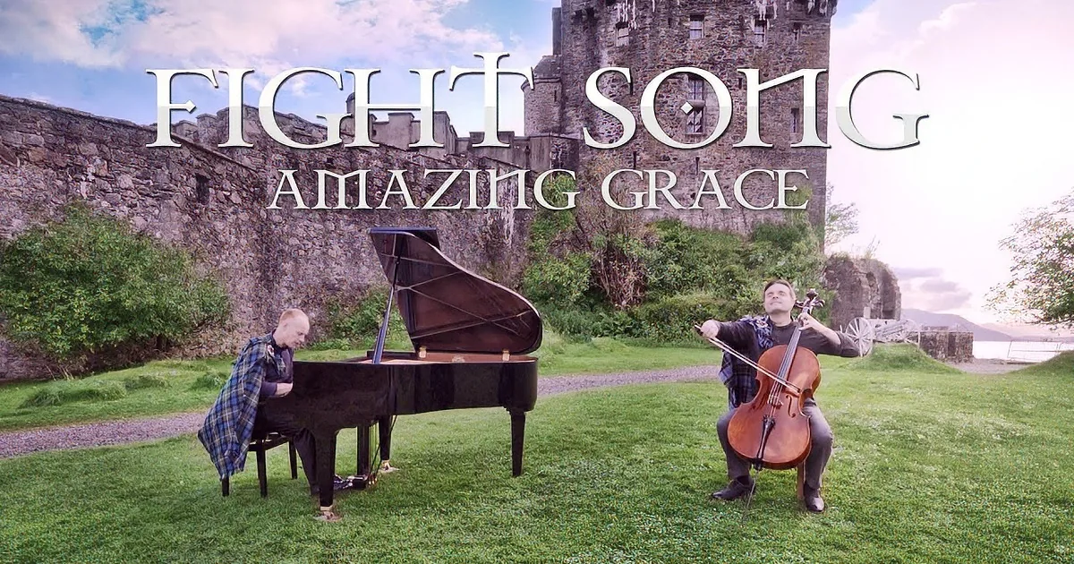 A man plays cello in front of a grand piano and another musician, with a castle backdrop.