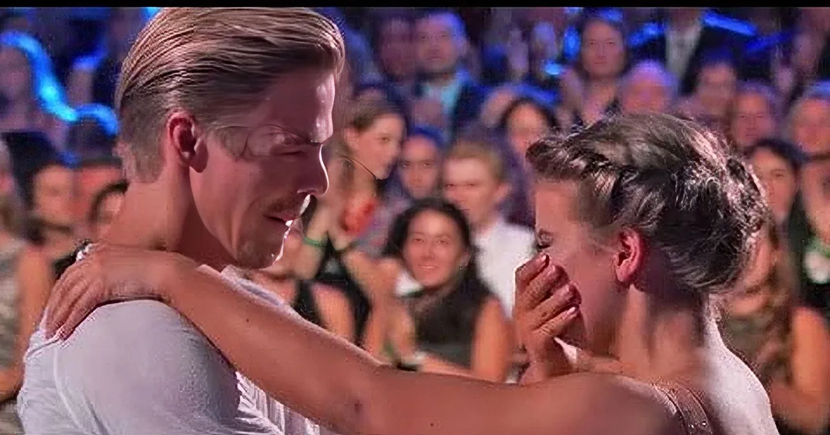 A man embraces a woman in front of a cheering crowd, with close-up shots of their faces and hands.