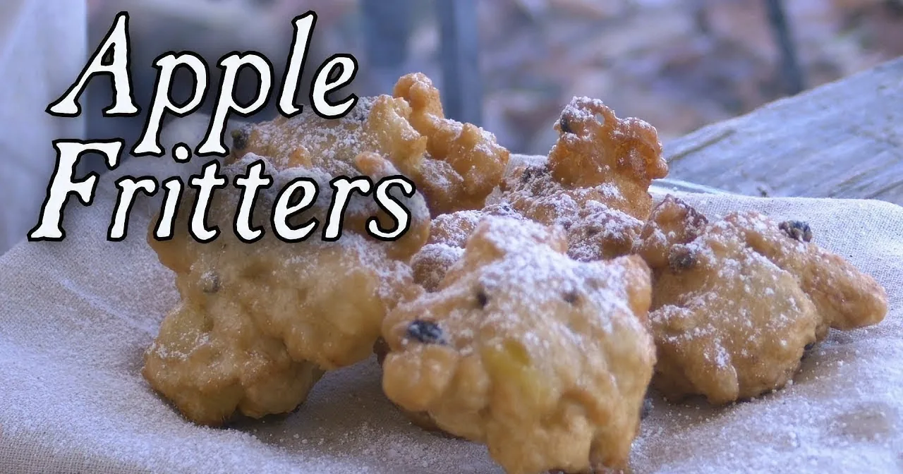 Golden apple fritters dusted with powdered sugar are displayed on a cloth.