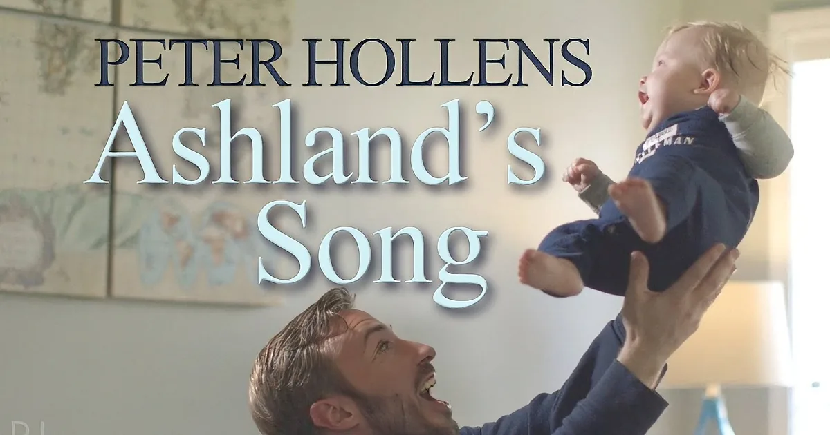 A man lifts a baby in the air, both smiling, with text overlay "Peter Hollens Ashland's Song."