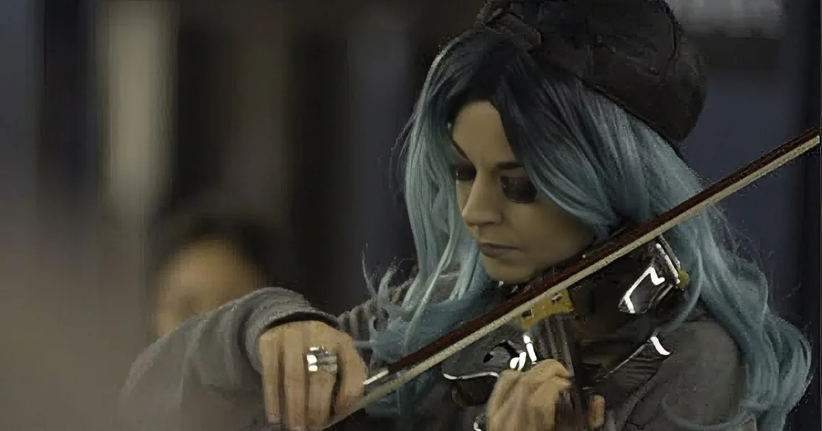 A person with blue hair and a black hat is playing a stringed instrument.