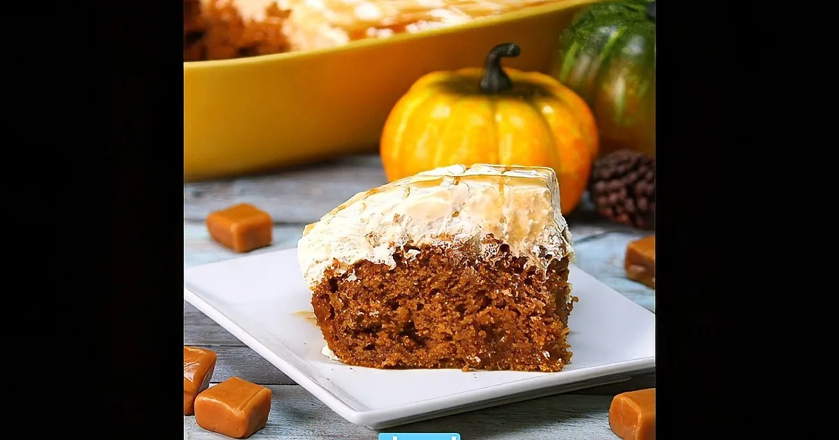 A slice of pumpkin cake with caramel sauce and whipped cream on a white plate.