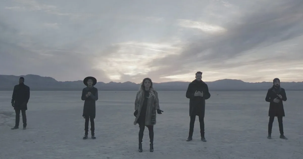 A group of people stands in a vast, snowy landscape under a cloudy sky, holding large, blank signs.