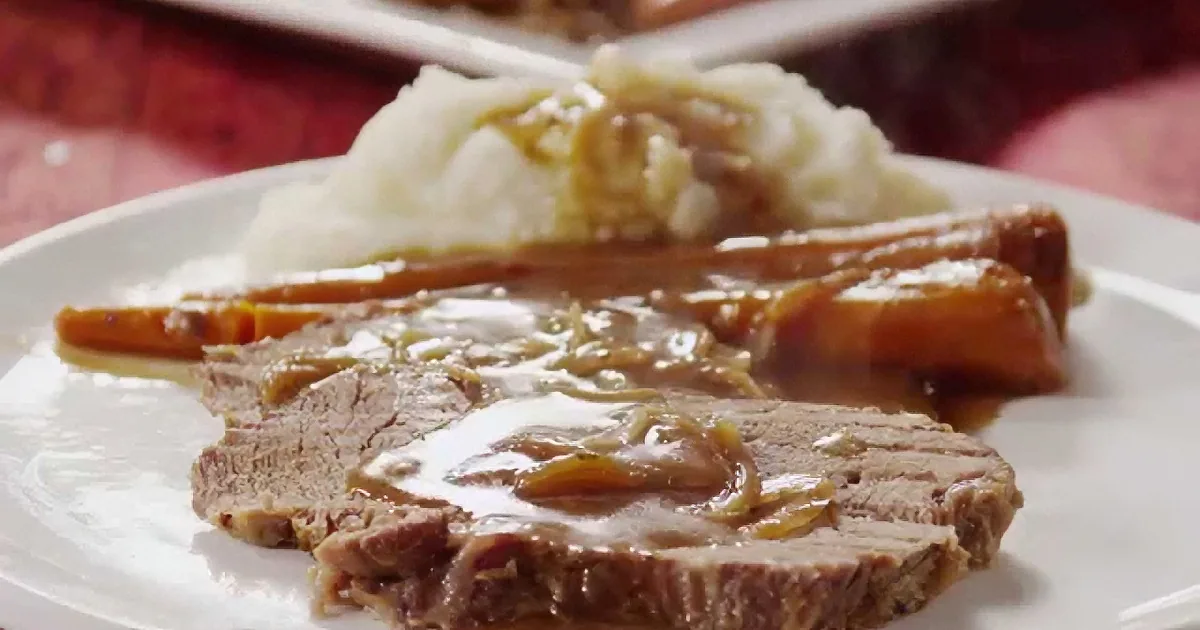 Sliced beef with gravy and mashed potatoes on a white plate.