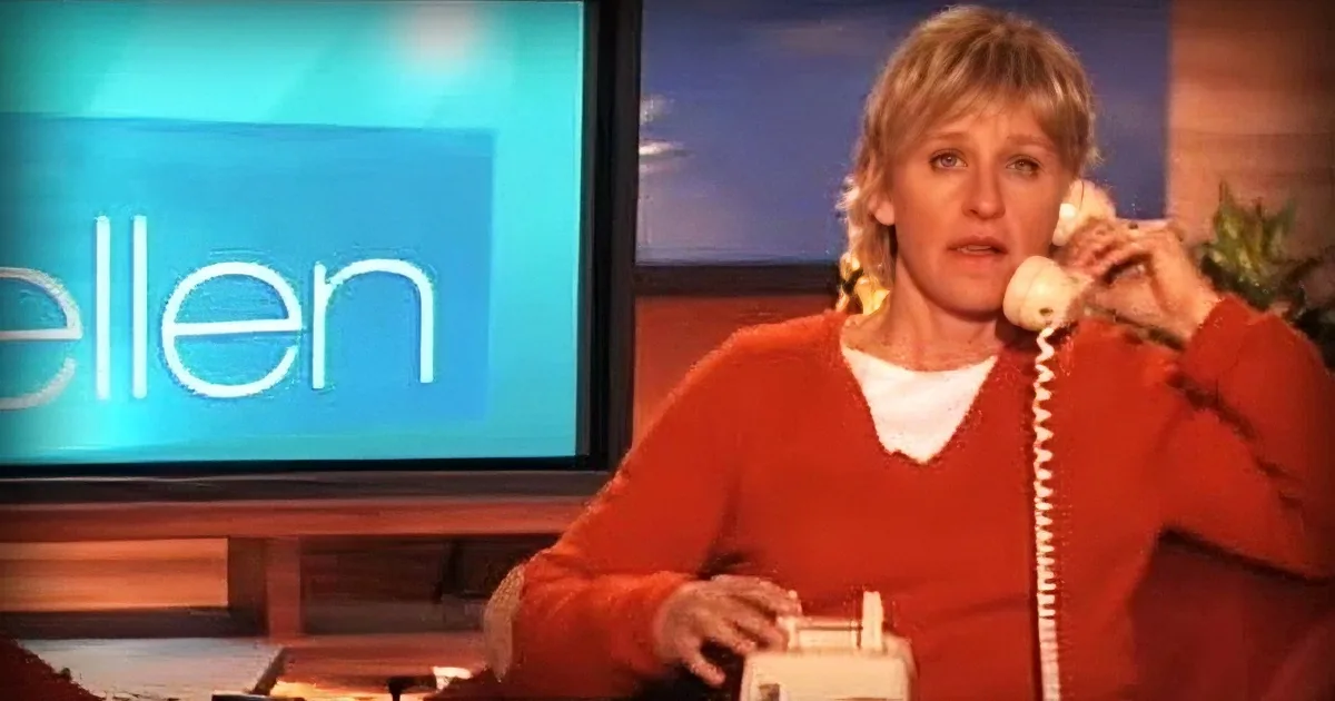A woman in a red jacket sits on a couch, holding a phone to her ear, with a TV screen in the background.