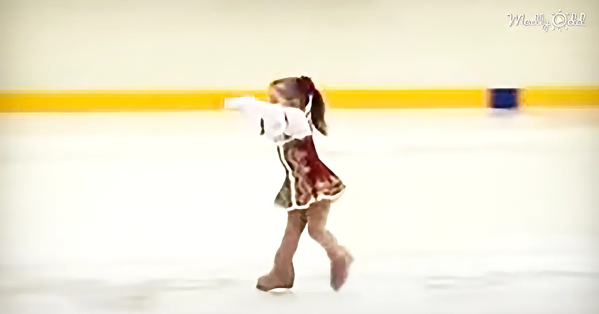 A young girl in a red and white outfit skates on an ice rink, arms outstretched.