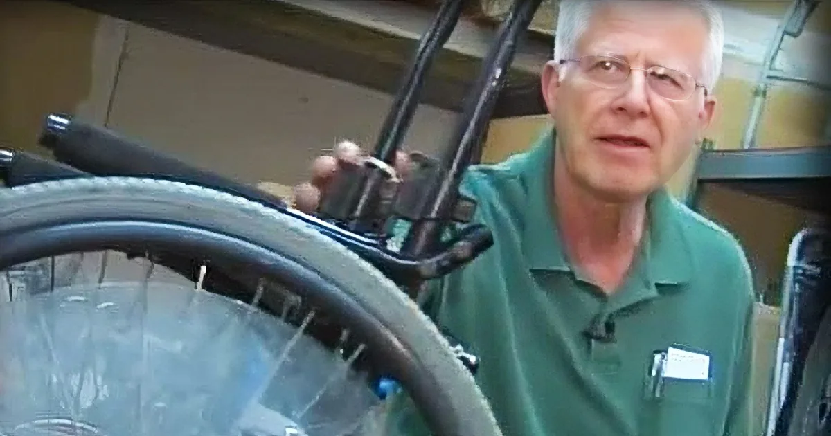 A man in a green shirt is holding a bicycle tire, explaining something about it.