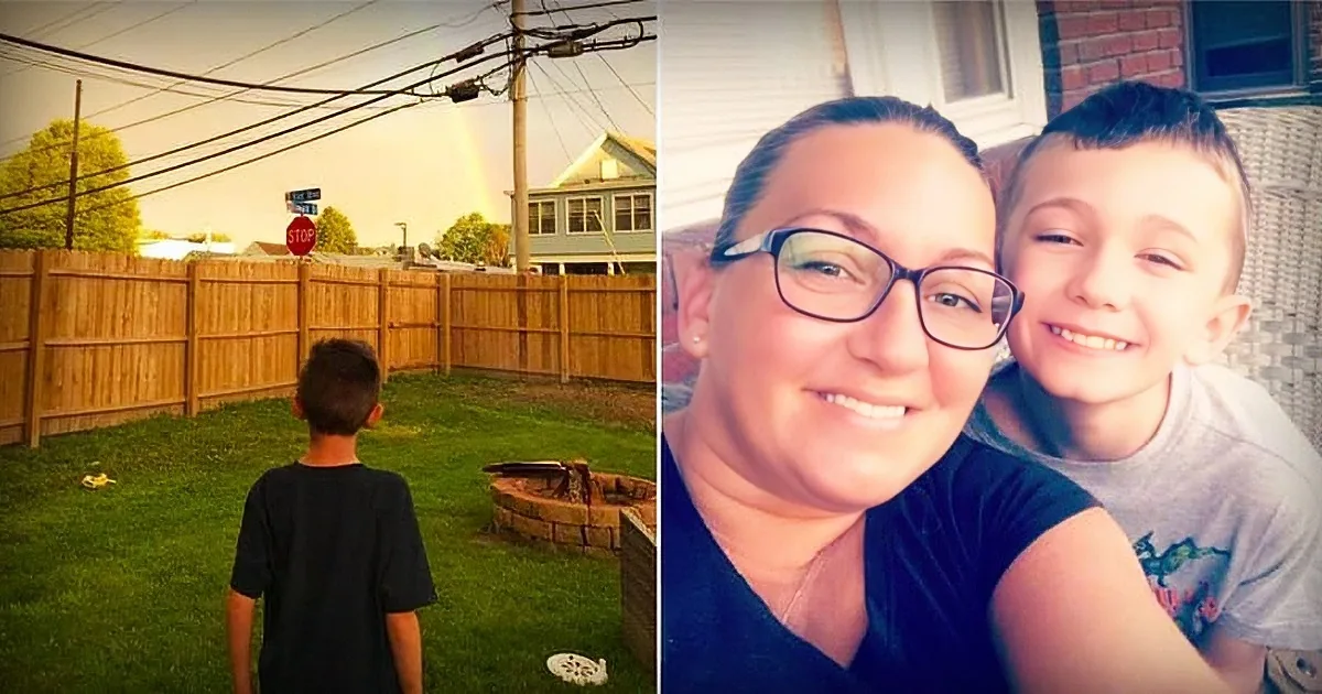 A woman and a boy smile in a selfie, with a rainbow and stop sign visible in the background.