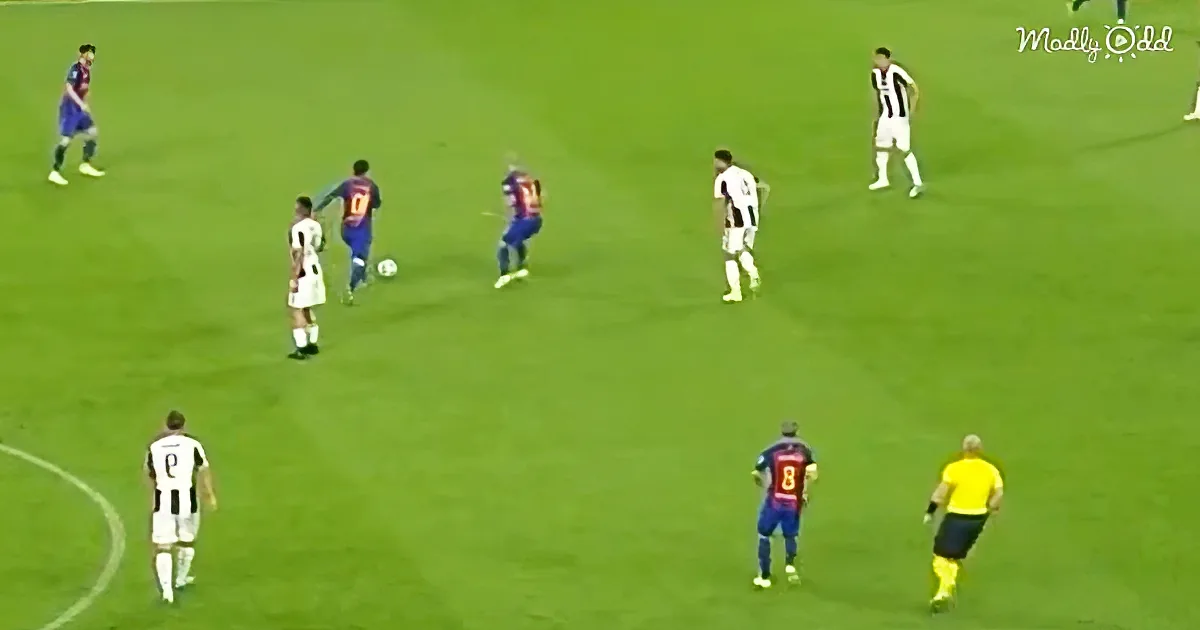 A soccer player in blue dribbles the ball while being pursued by players in white and a referee in yellow.