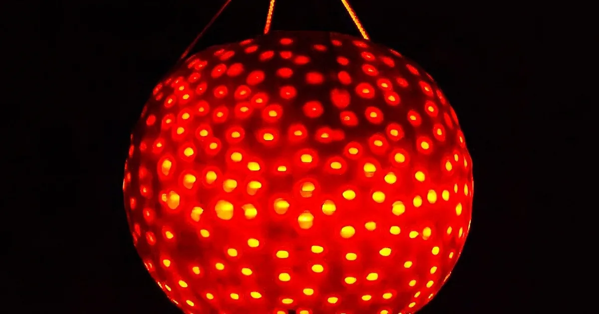 A glowing red spherical object with numerous small, bright yellow dots against a dark background.