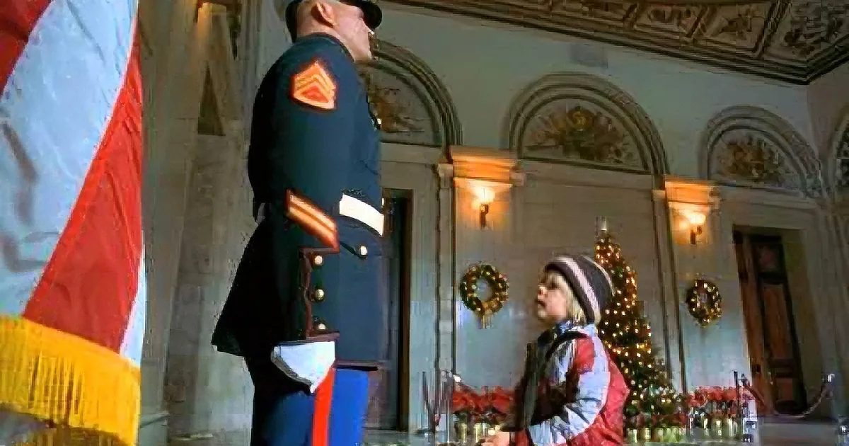 A soldier in uniform stands at attention next to a child in a festive setting with a Christmas tree.