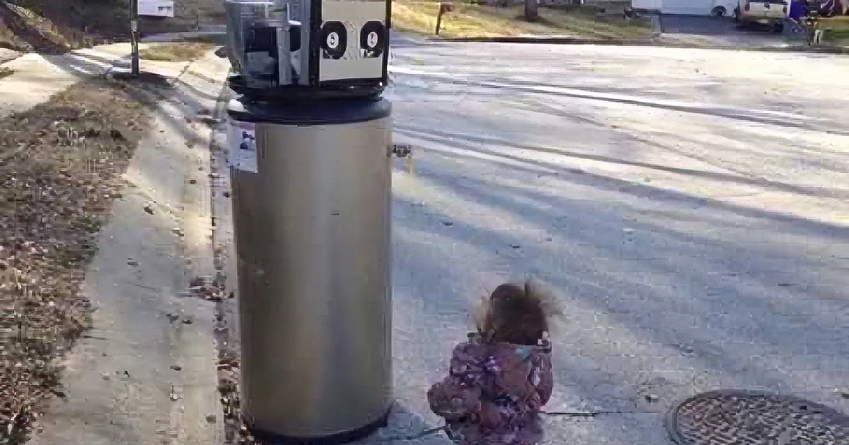 A young girl in a purple jacket walks past a large cylindrical object on a sidewalk near a street.