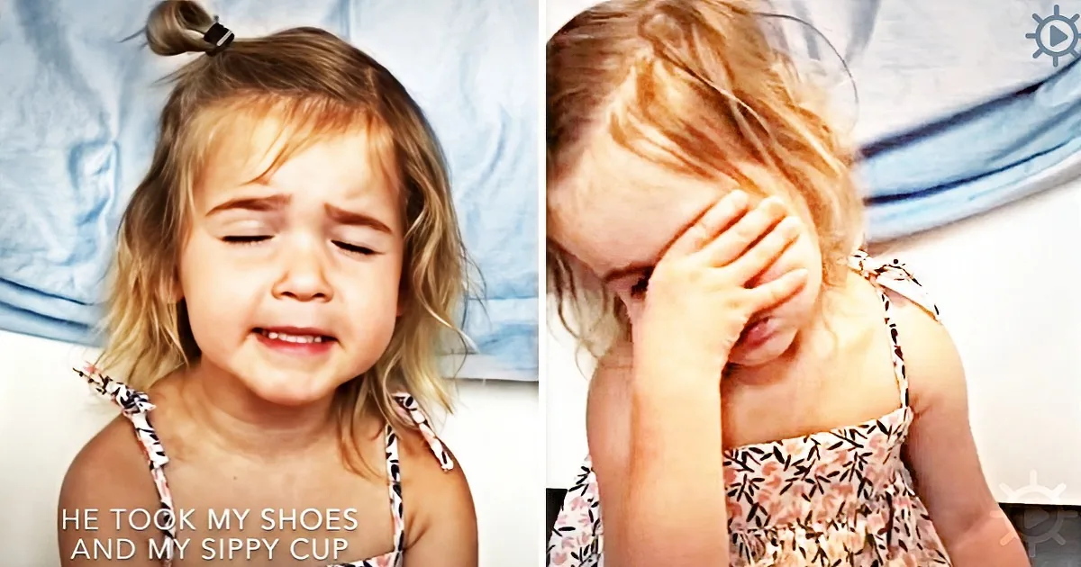 A young girl with blonde hair, wearing a floral dress, is visibly upset, covering her face with her hands.