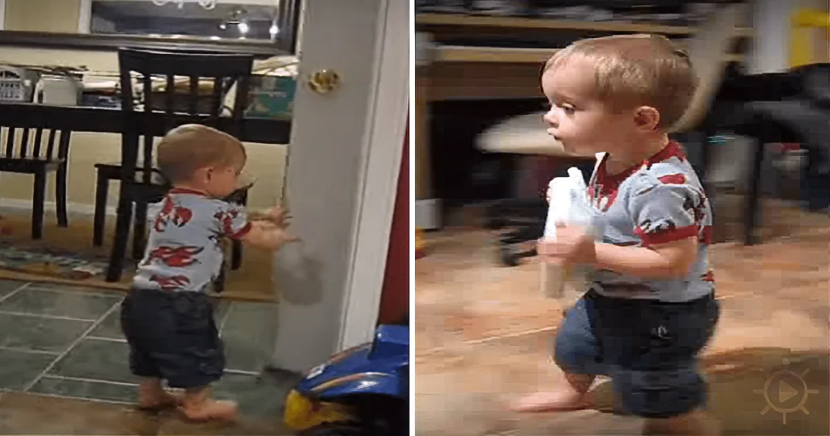 A toddler in a kitchen, holding a white object, appears to be walking or moving forward.