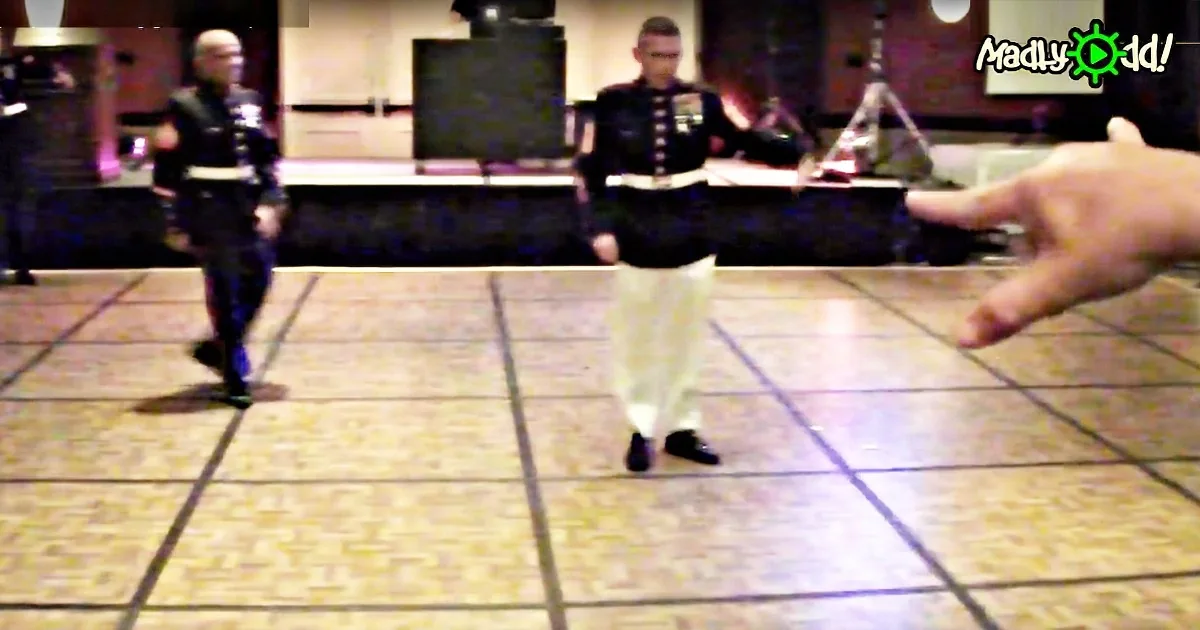 A person in a black uniform stands on a tiled floor, while another in a white uniform stands nearby.