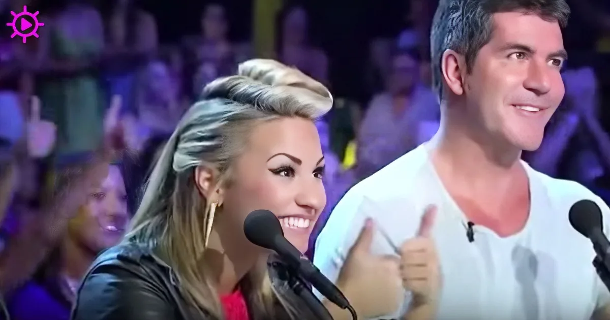 A woman with a microphone gives a thumbs-up, smiling, with a man in a white shirt also giving a thumbs-up.