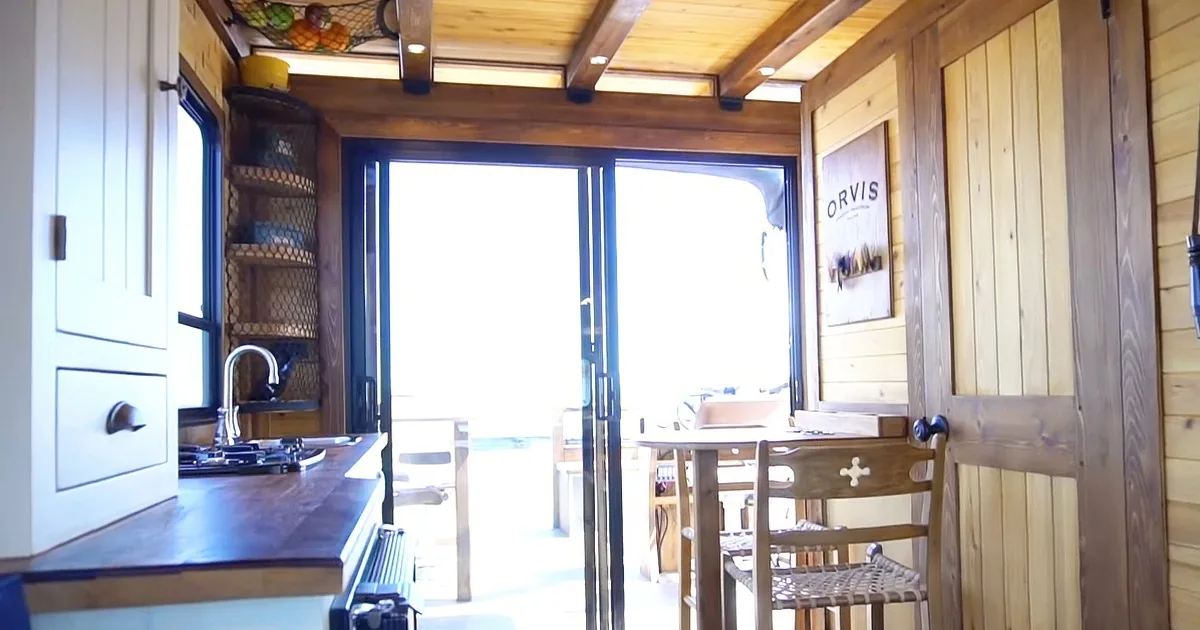 A cozy kitchen with wooden cabinets, a sink, and a sliding glass door leading to a bright outdoor area.