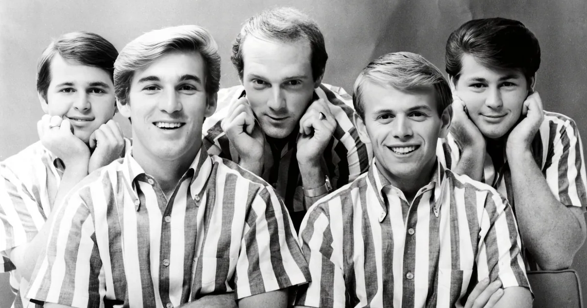 Five young men in striped shirts pose together, smiling and resting their chins on their hands.