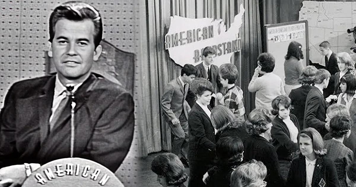 A man in a suit sits in front of a backdrop with "American" text, while a crowd of people stands in a room with a map and...