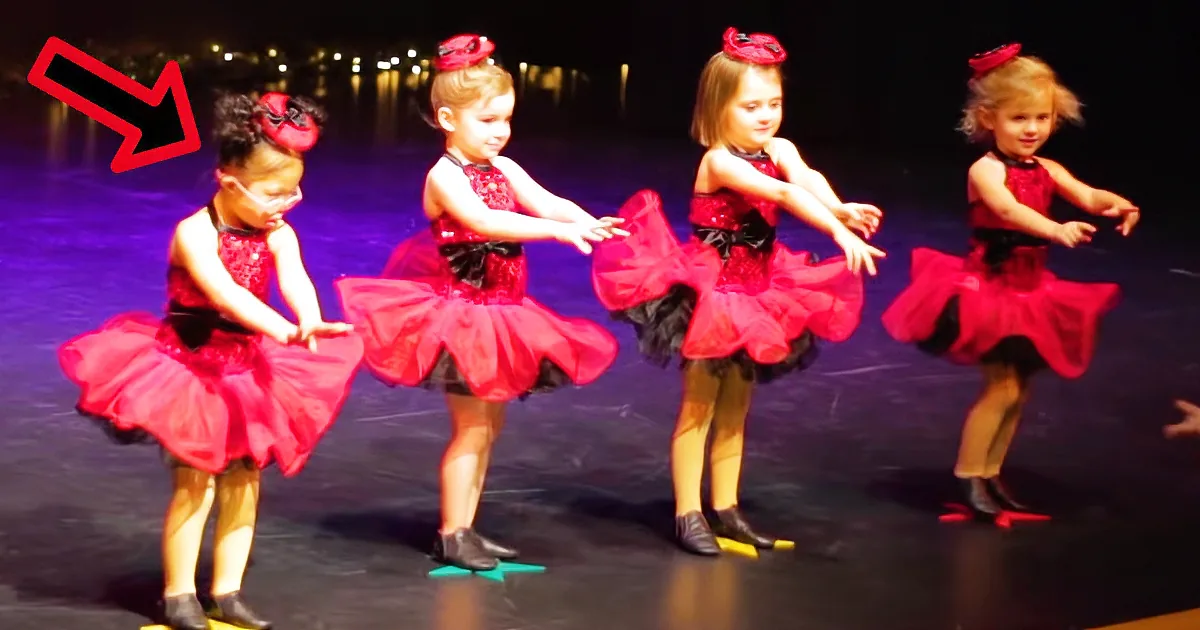 Four young dancers in red tutus perform a synchronized routine on stage.