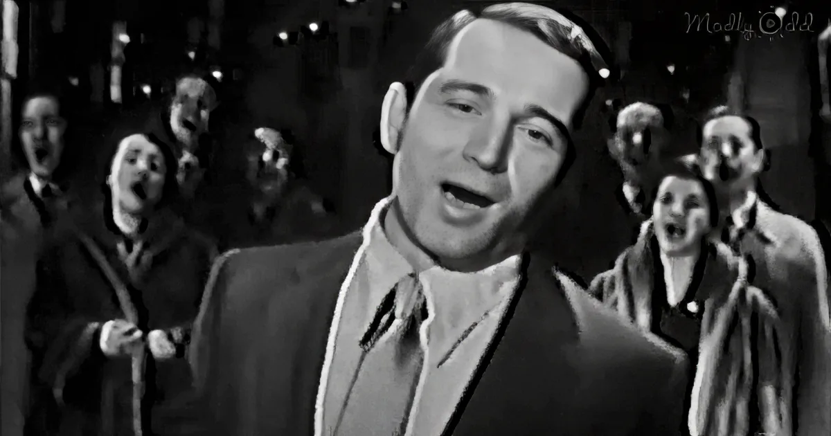 A man in a suit sings passionately, surrounded by a group of people also singing.