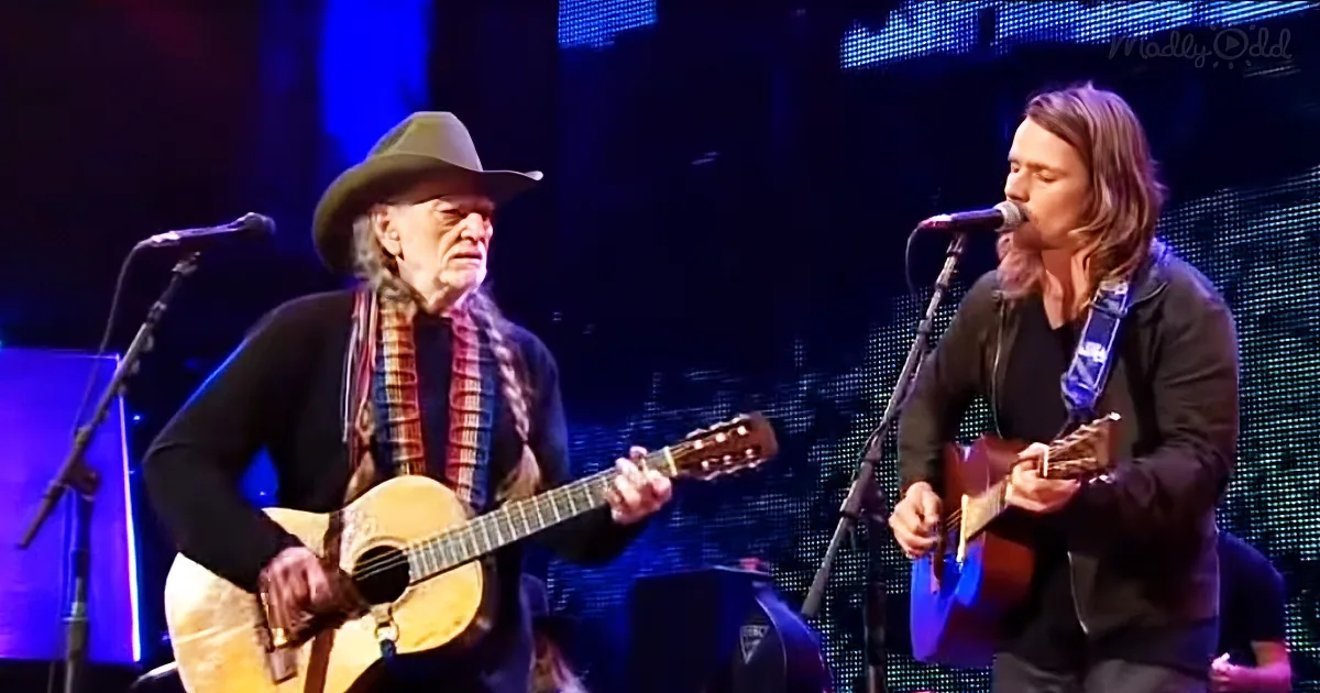 Two musicians perform on stage, one playing guitar and singing, the other playing an acoustic guitar.