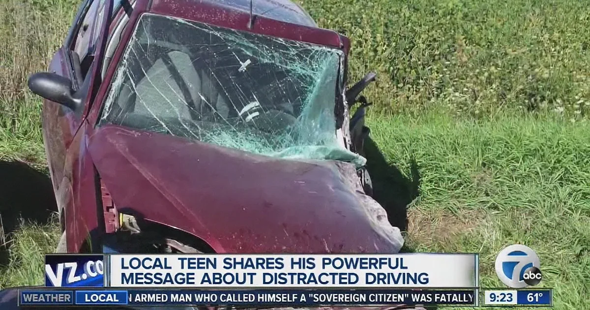 A maroon car with a shattered windshield lies in a grassy field, emphasizing the dangers of distracted driving.