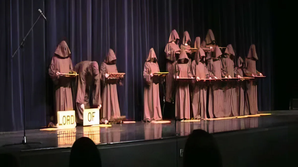 Monks in robes stand on stage holding trays, with "LORD OF" sign visible.