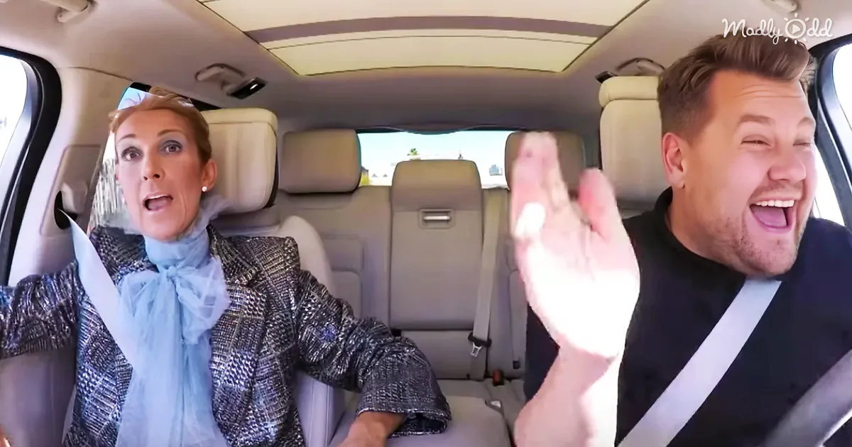 A woman in a checkered blazer and a man in a black shirt are in a car, both appearing animated and expressive.