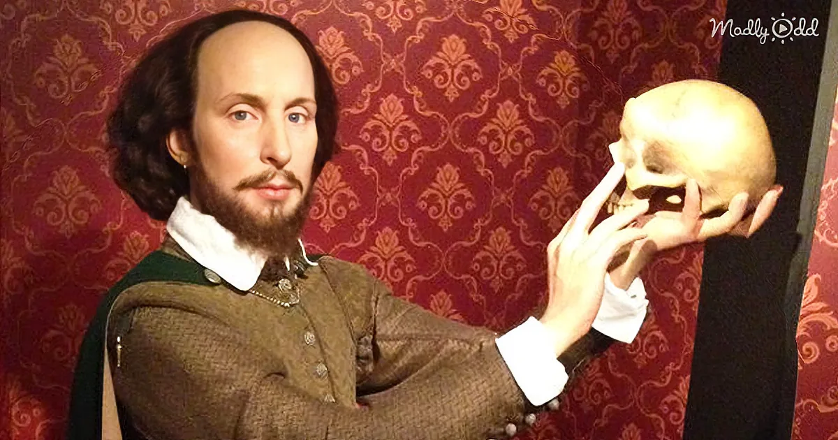 A wax figure of William Shakespeare holds a skull against his cheek, dressed in period attire.