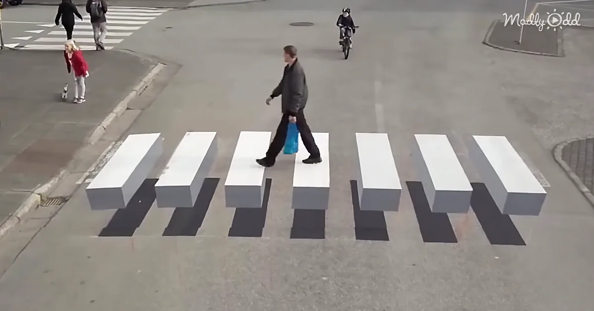 A man walks across a street with white blocks resembling a zebra crossing, creating an optical illusion.