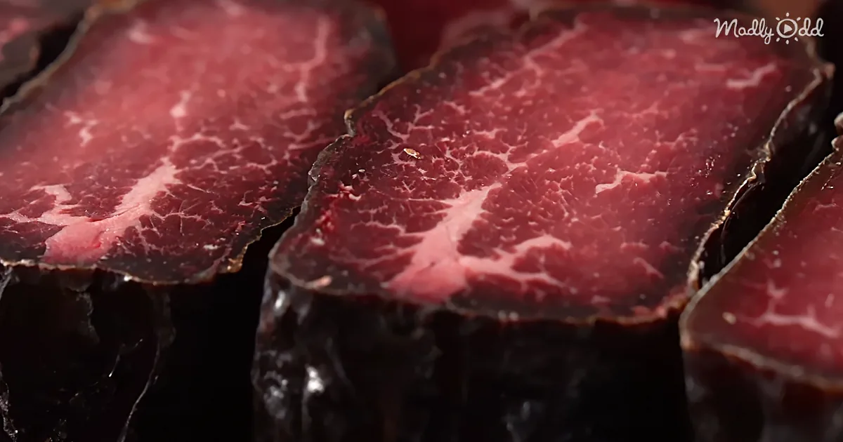 Slices of dark, richly marbled meat, possibly beef, with a glossy texture and deep red color.