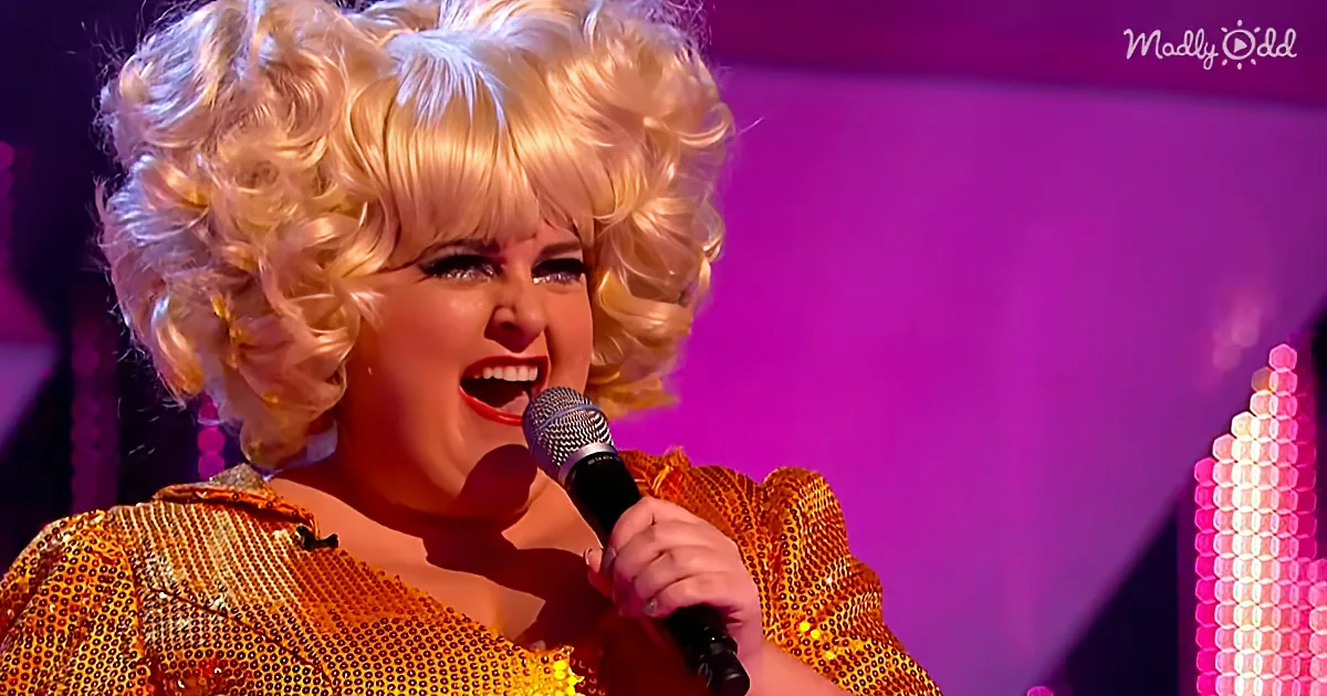 A person in a glittery gold outfit sings into a microphone on stage with a vibrant purple background.