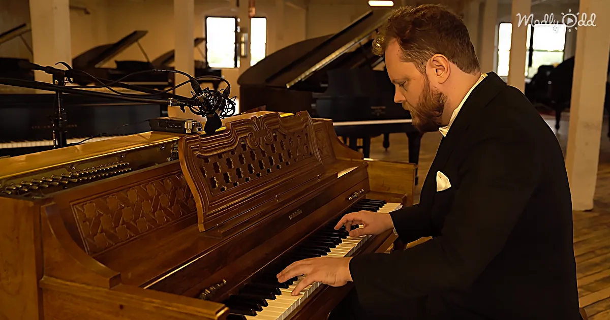 A man in a suit plays a vintage organ in a room with pianos and microphones.