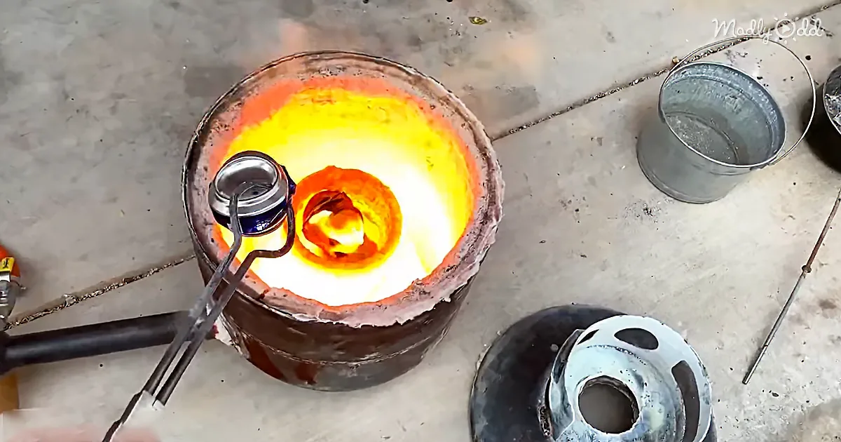 A molten metal crucible glows brightly, with a small can inside, surrounded by tools and a bucket on a concrete floor.