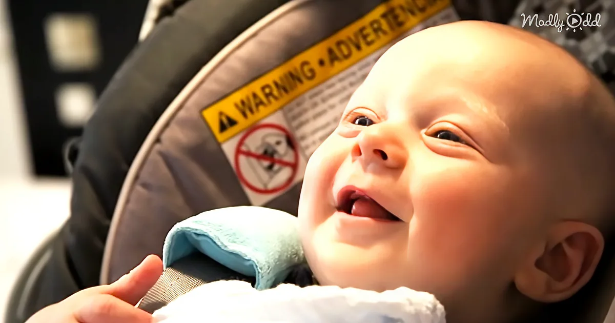 A smiling baby in a car seat with a warning label visible in the background.
