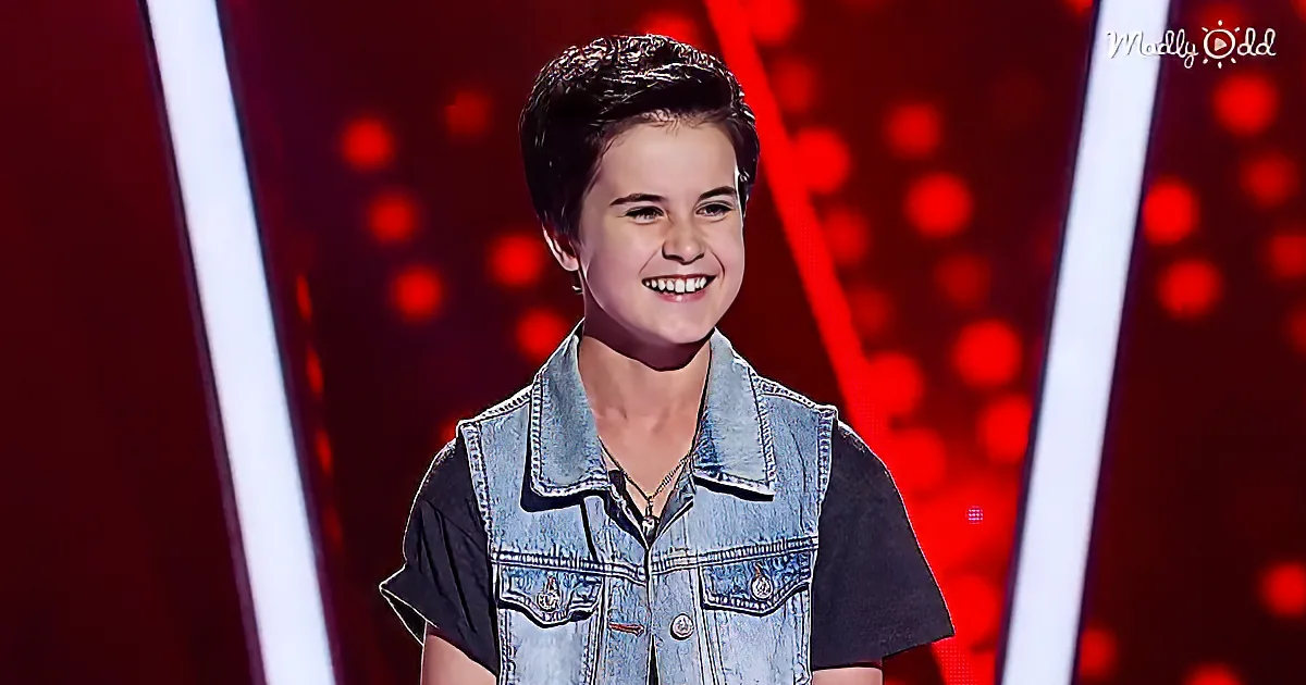 A smiling young person in a denim vest and black shirt stands against a red, illuminated background.