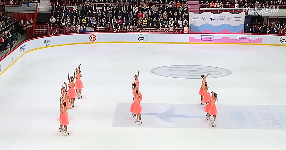 Skaters in pink dresses perform synchronized routine on ice rink.