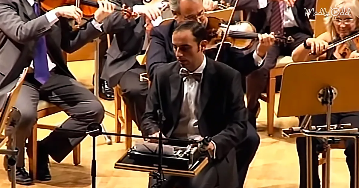 A man in a tuxedo sits at a piano, surrounded by musicians playing string instruments.