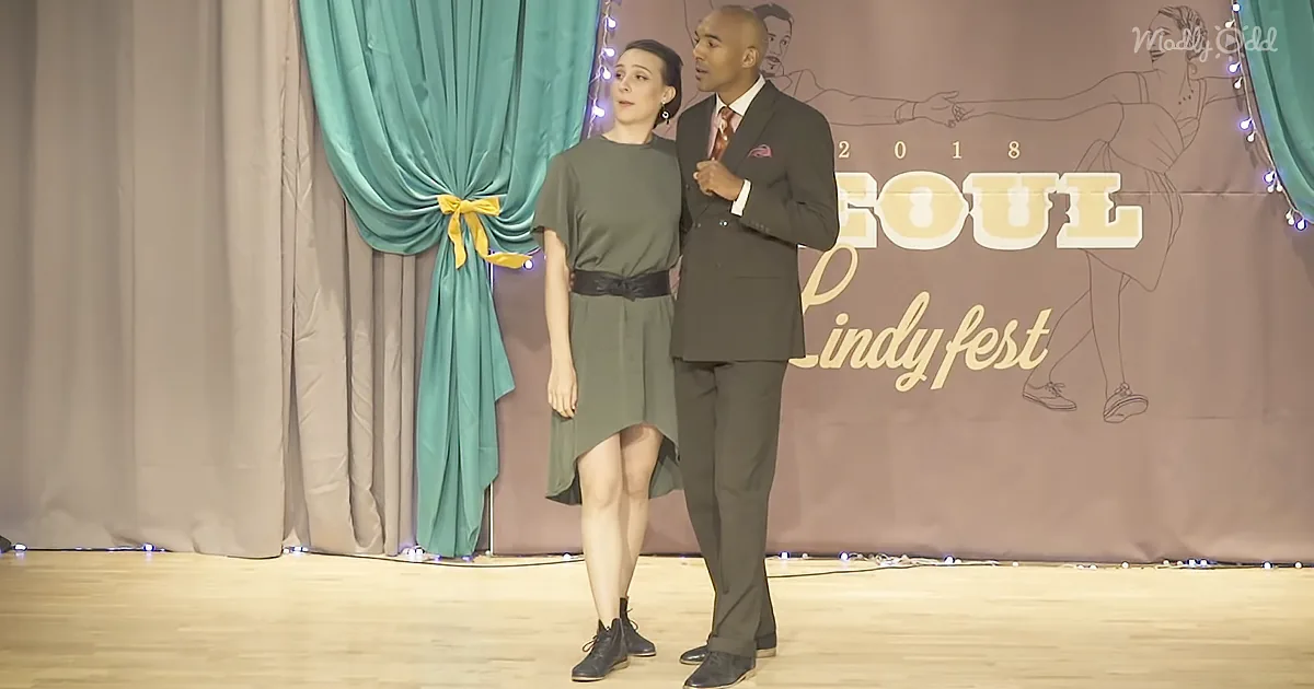 A man in a suit and a woman in a dress stand on stage at the Soul Lindyfest 2018.