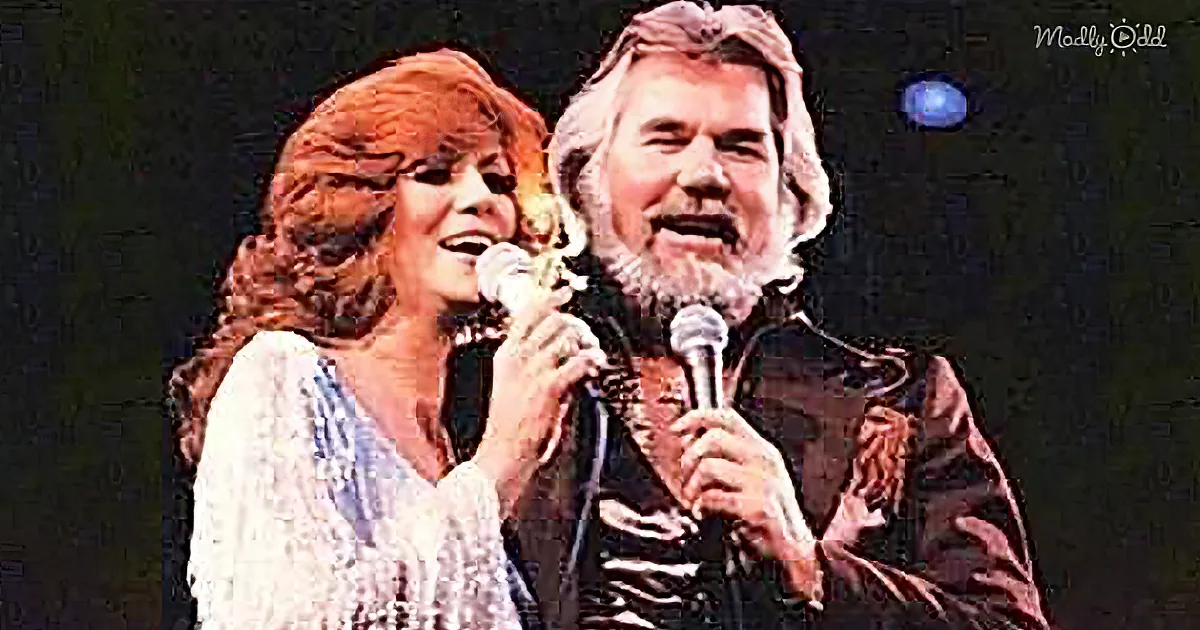 A man and woman are singing on stage, both holding microphones, with a dark background and a "Madly Odd" watermark.