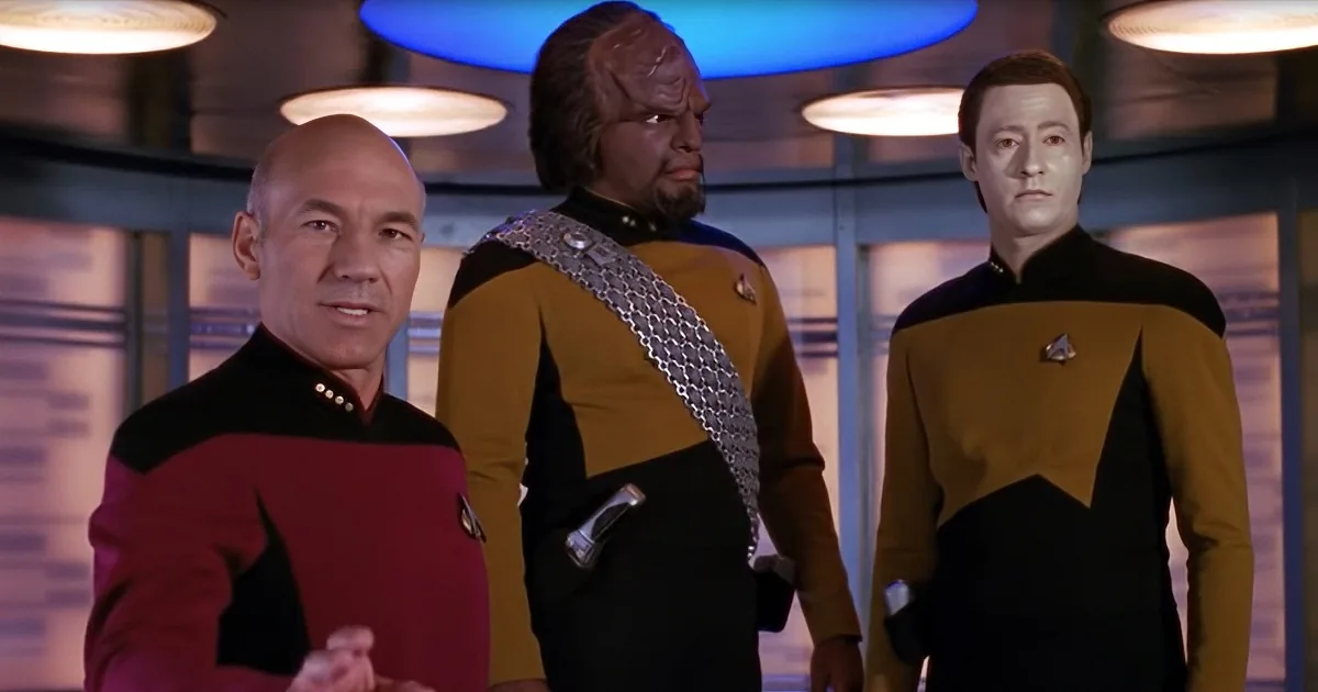 Captain Picard, Worf, and Data in Star Trek uniforms, standing together in a ship's interior.